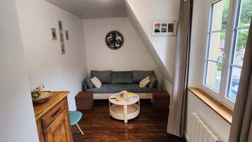 A cozy room with a wooden floor, a sofa, a small round table, and a cabinet.