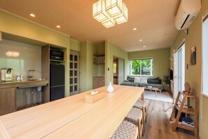 A modern kitchen with a long wooden island, built-in appliances, and a dining area with a wooden table and chairs.