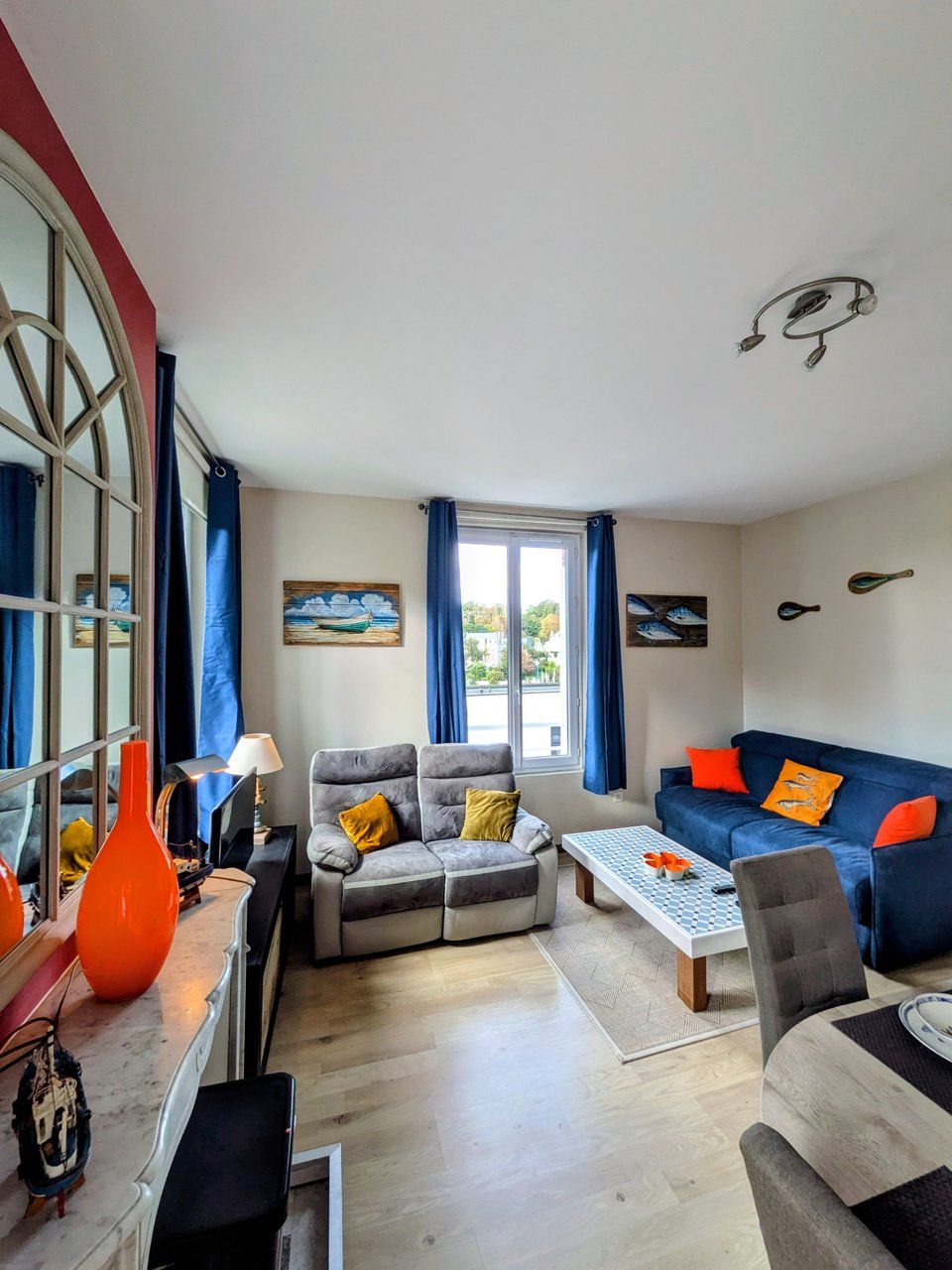 Uma sala de estar com sofá, poltronas, mesa de centro e um espaço de jantar com mesa e cadeiras.