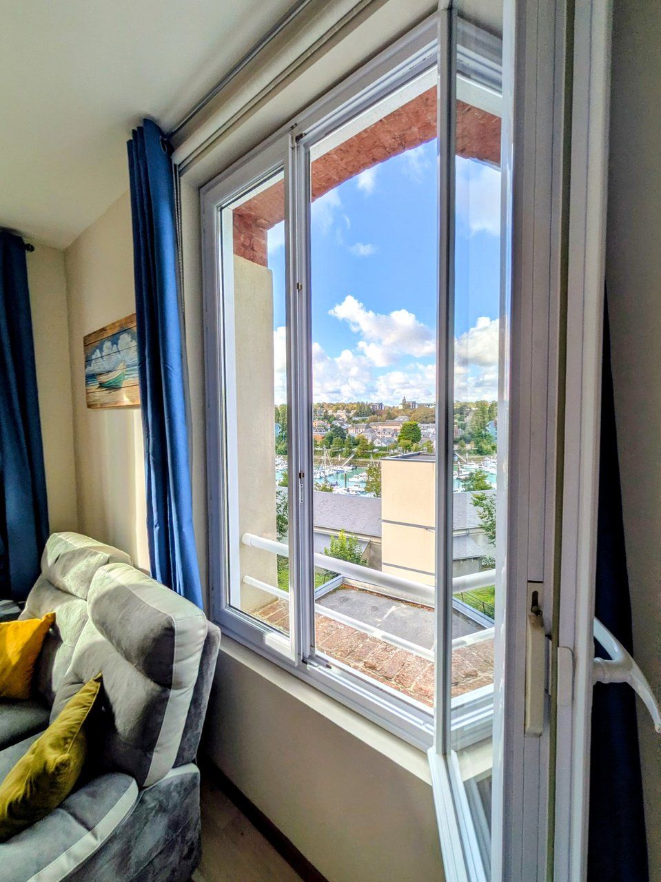 Une pièce avec une grande fenêtre, un canapé et un tableau accroché au mur.