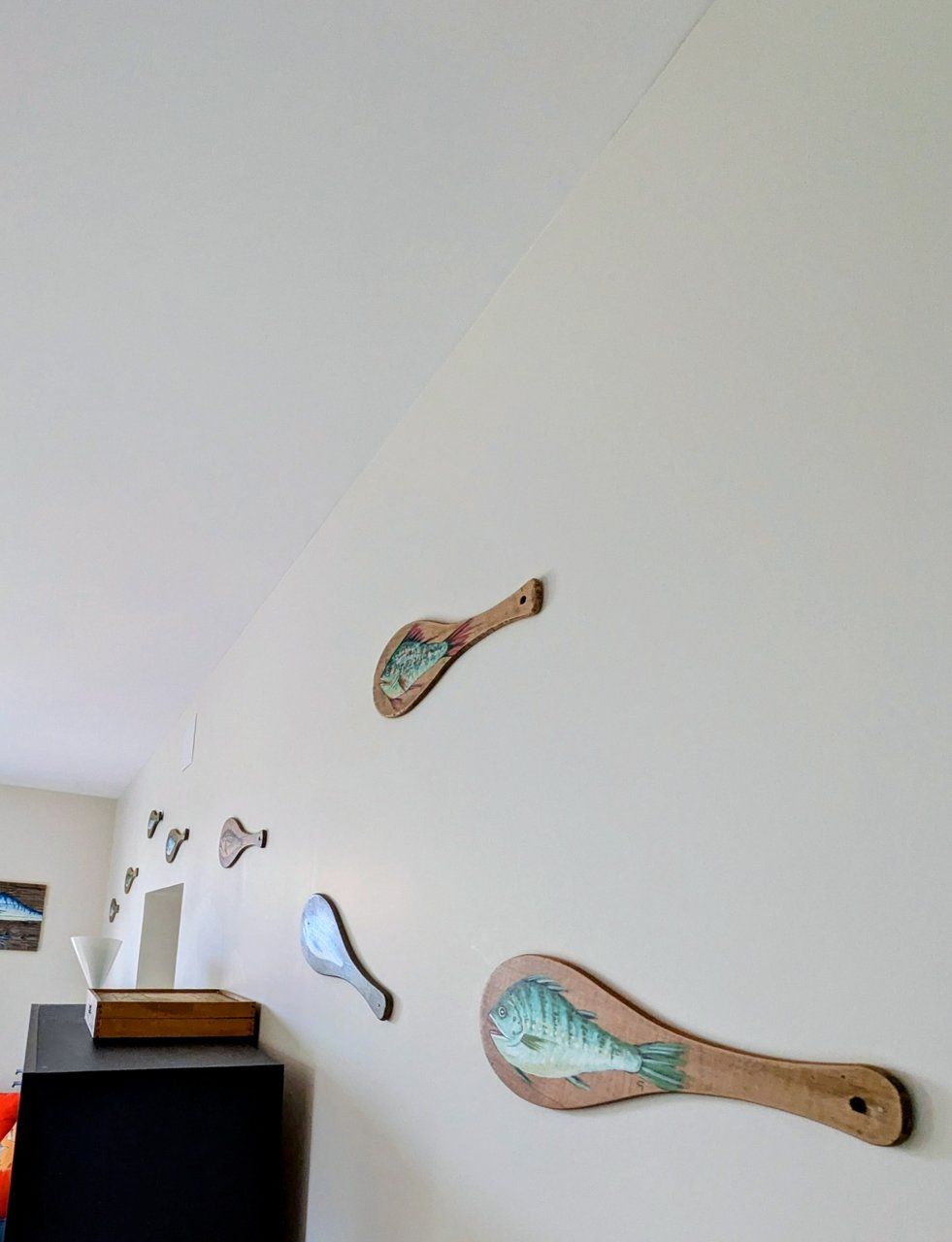 Un mur orné de divers objets en bois ayant la forme de poissons.