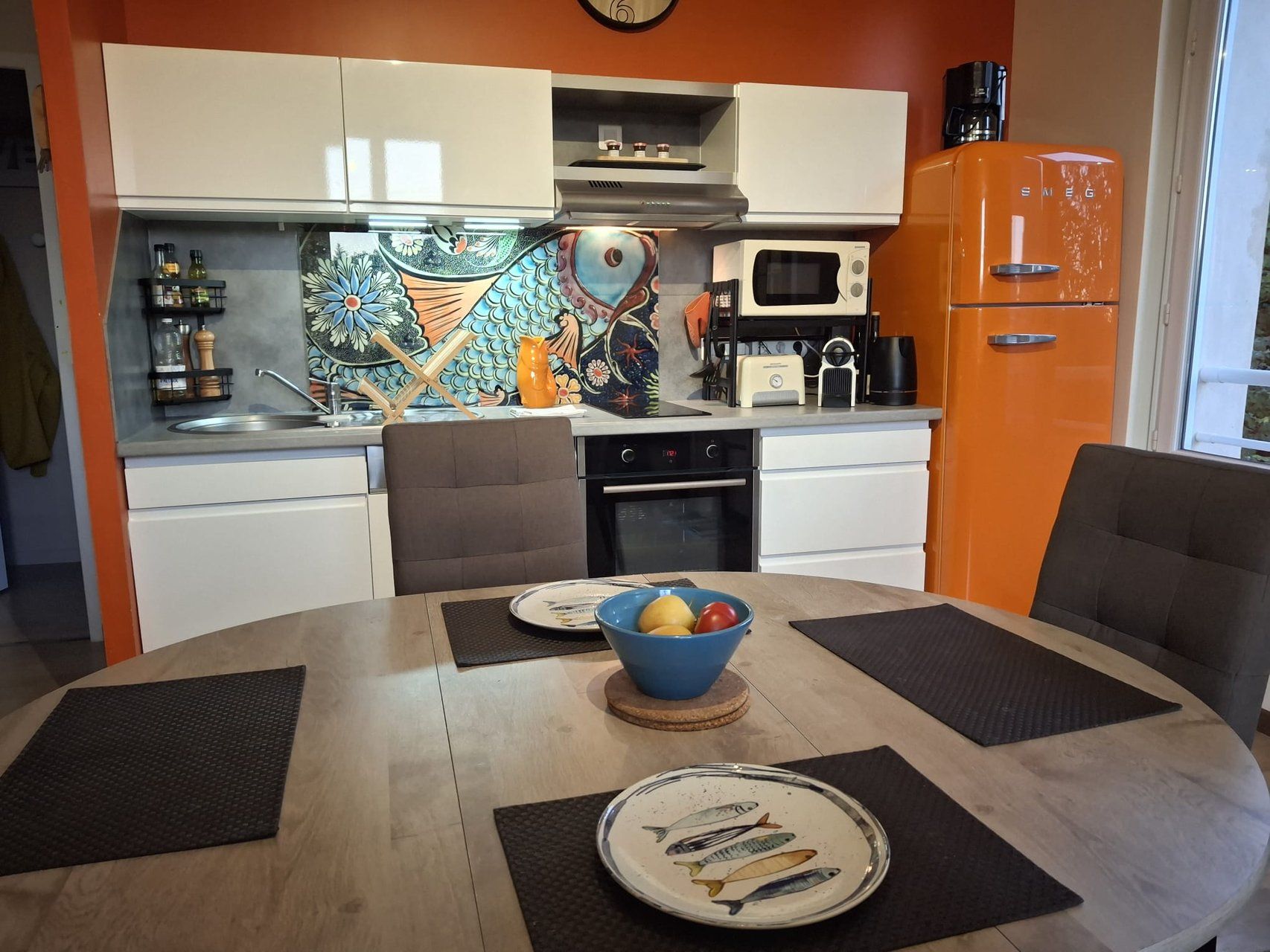 A modern kitchen with white cabinets, a microwave, a coffee maker, and a vintage orange refrigerator.
