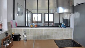 Una cocina moderna con un ventanal grande, horno empotrado y encimera con diversos objetos.