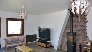 Una sala de estar moderna con televisión, sofá, mesa de centro, chimenea y una lámpara de techo esférica única.