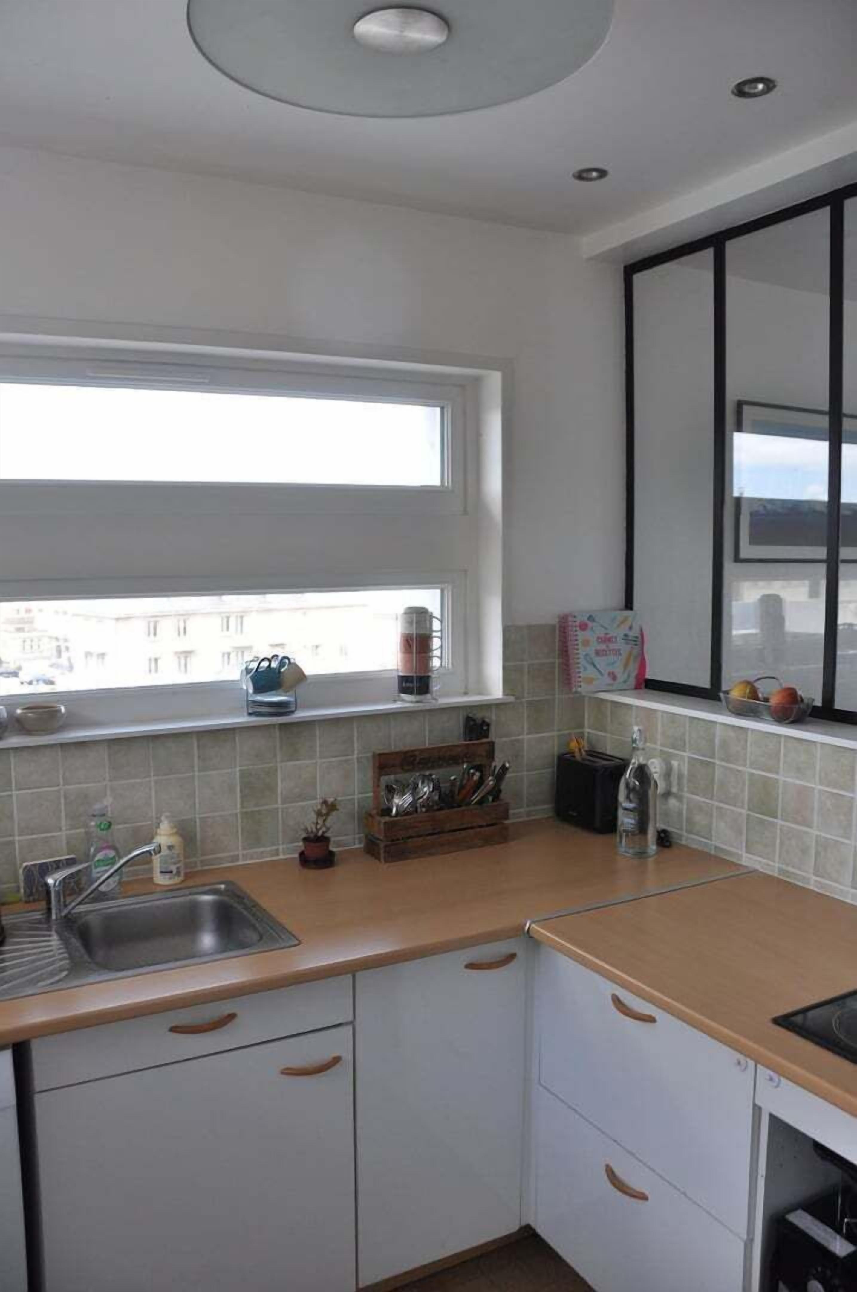 Una cocina con ventana, lavamanos y armarios.