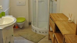 A bathroom with a shower, toilet, sink, and wooden vanity.