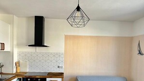 A compact kitchen with a built-in oven, a wooden countertop, and a modern pendant light.