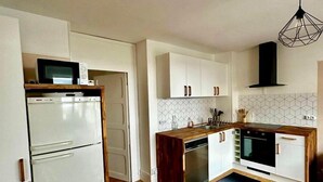 A modern kitchen with white cabinets, a wooden countertop, a built-in oven, and a microwave.