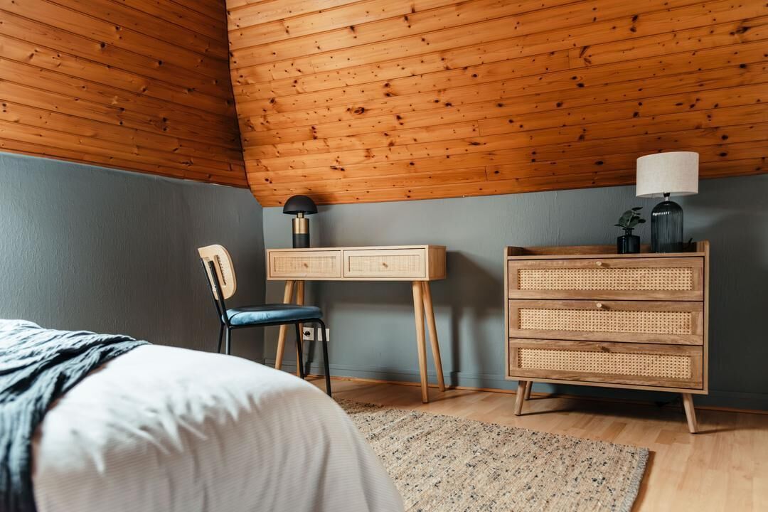 A room with a bed, a desk, a chair, and a dresser.