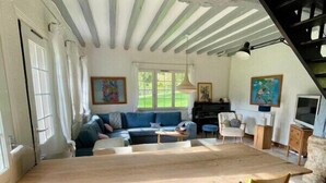 A spacious living area with a large wooden table and chairs, a sofa, and a staircase.