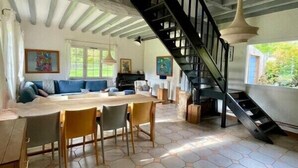 A spacious living area with a hexagonal tiled floor, a black spiral staircase, and a dining area with wooden chairs and a table.