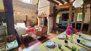 Ein rustikaler Essbereich mit Kamin aus Backstein, Holzbalken und einem für eine Mahlzeit gedecktem Tisch.