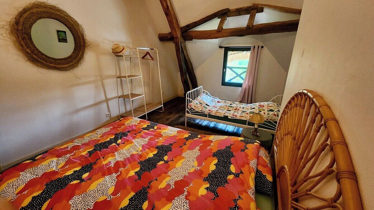 A bedroom with a bed, a hanging chair, a ladder, and a window.