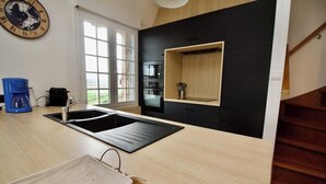 A modern kitchen with a black backsplash, wooden countertops, a built-in oven, and a large window. - Apartment with superb sea and land views (Veulettes-sur-Mer)