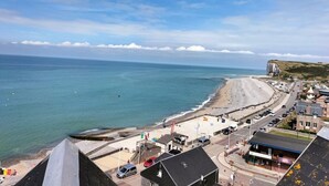 A coastal town with a beach, buildings, and a road leading to the sea. - Apartment with superb sea and land views (Veulettes-sur-Mer)