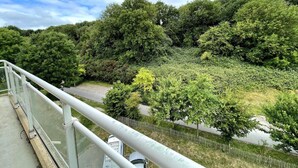 A bridge with a metal railing overlooking a river and dense greenery. - Roirand | Romantic Beach on Foot (Veules-les-Roses)