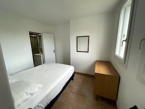 A bedroom with a bed, a wooden dresser, a mirror, and a window. - Roirand | Romantic Hideaway in Veules-les-Roses • Beach on Foot (Veules-les-Roses)