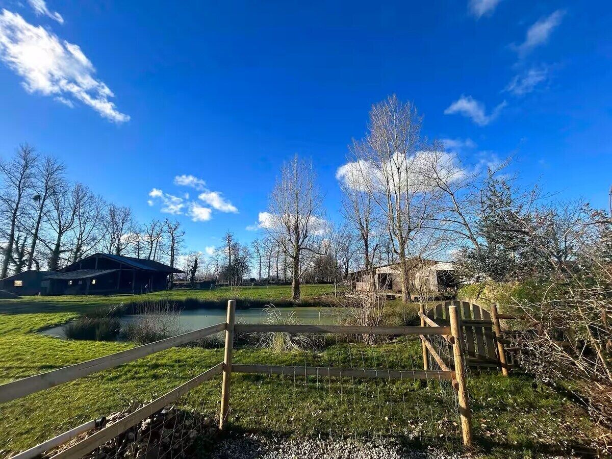 A park with a pond, wooden structures, and a clear blue sky.