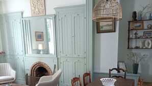 Un coin repas avec une table et des chaises en bois, un luminaire suspendu et une cheminée.