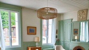 Un salon chaleureux avec une table basse en bois, des canapés bleus et blancs, une cheminée et une grande fenêtre donnant sur un paysage verdoyant.