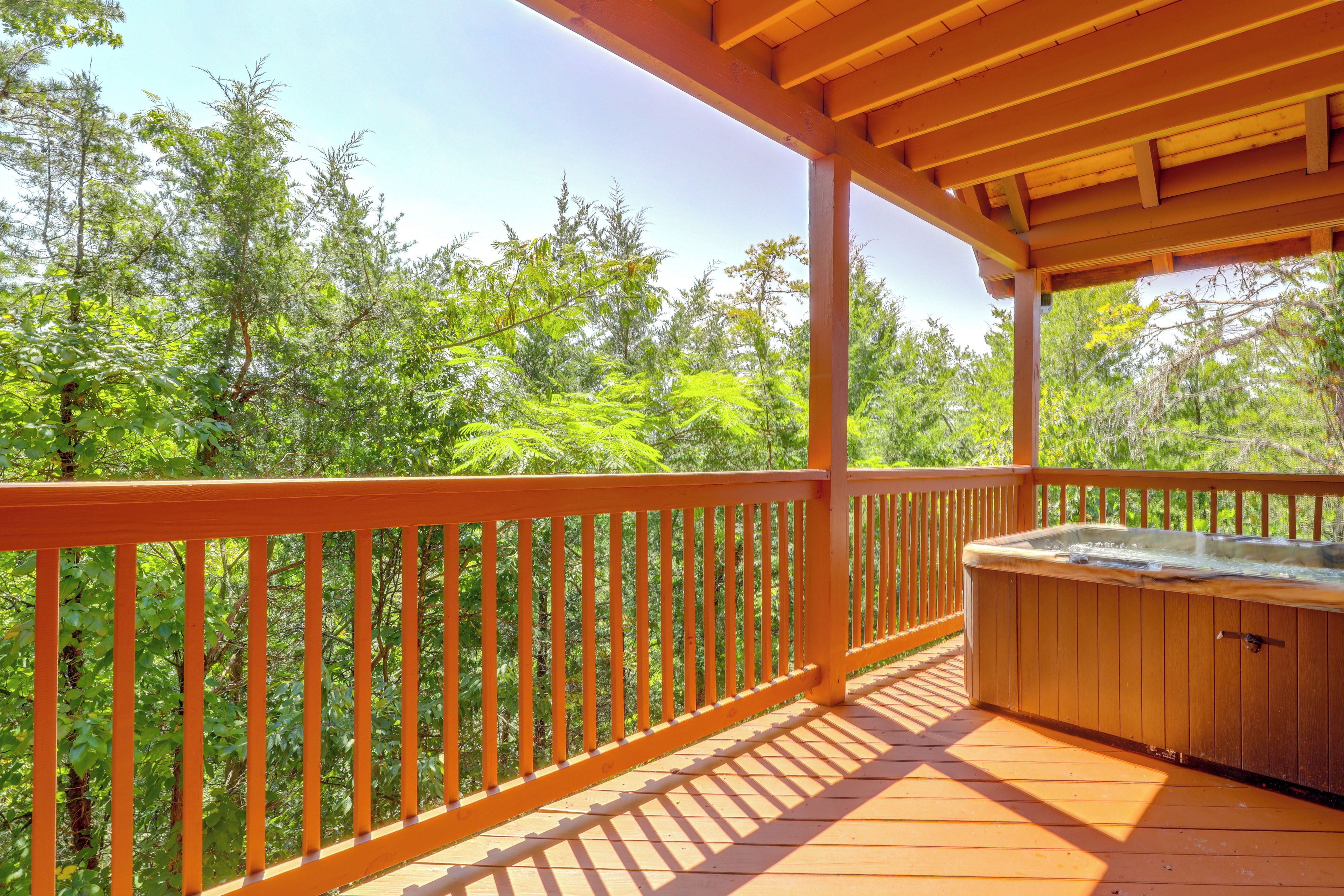 Une terrasse en bois avec un jacuzzi, entourée d’une végétation luxuriante.