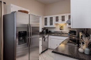 A modern kitchen with stainless steel appliances, white cabinetry, granite countertops, and a backsplash. - Entire Duplex! Downtown 4 Bdr - King beds (Anchorage)