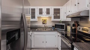 Una cocina moderna con electrodomésticos de acero inoxidable, armarios blancos y encimera de granito.