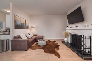 A modern living room with a sectional sofa, a flat-screen TV, a fireplace, and a cowhide rug. - Entire Duplex! Downtown 4 Bdr - King beds (Anchorage)