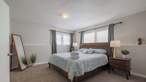 Un dormitorio con cama, mesitas de noche, un espejo y una ventana.