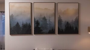 Una pared con tres cuadros enmarcados que muestran un paisaje boscoso.
