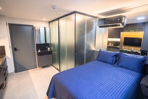 Quarto moderno com cama grande, guarda-roupa, penteadeira com espelho e ar-condicionado instalado no teto.