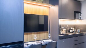 Une cuisine compacte équipée d’un four à micro-ondes, d’un évier et d’un coin repas avec deux chaises et une table dressée pour deux personnes.