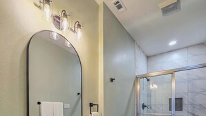 A bathroom with a granite countertop sink, a large mirror, a toilet, and a glass-enclosed shower. - Enjoyable 2-bedroom house with AC  1min from Kickapoo Lucky Eagle Casino. (Eagle Pass)