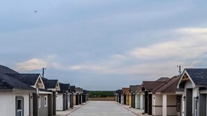 A row of single-story buildings with a central driveway. - Enjoyable 2-bedroom house with AC  1min from Kickapoo Lucky Eagle Casino. (Eagle Pass)
