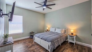 A bedroom with a bed, two bedside tables, a ceiling fan, a window with blinds, and a small plant on a nightstand. - Enjoyable 2-bedroom house with AC  1min from Kickapoo Lucky Eagle Casino. (Eagle Pass)