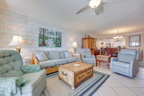 A living room with a sofa, armchairs, a coffee table, and a cabinet.
