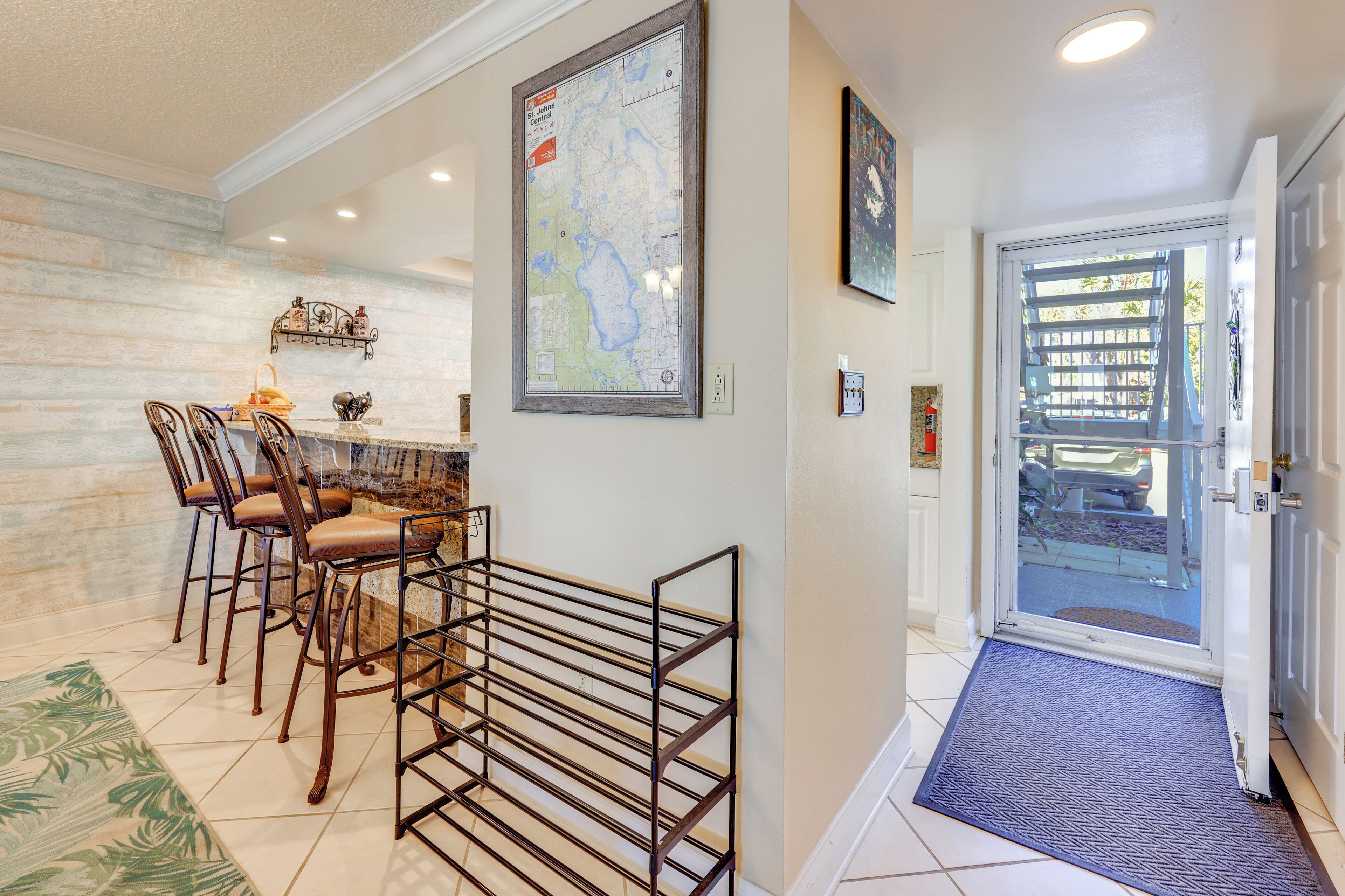 A dining area with a map on the wall, a metal rack, and a door with a view of the outside.