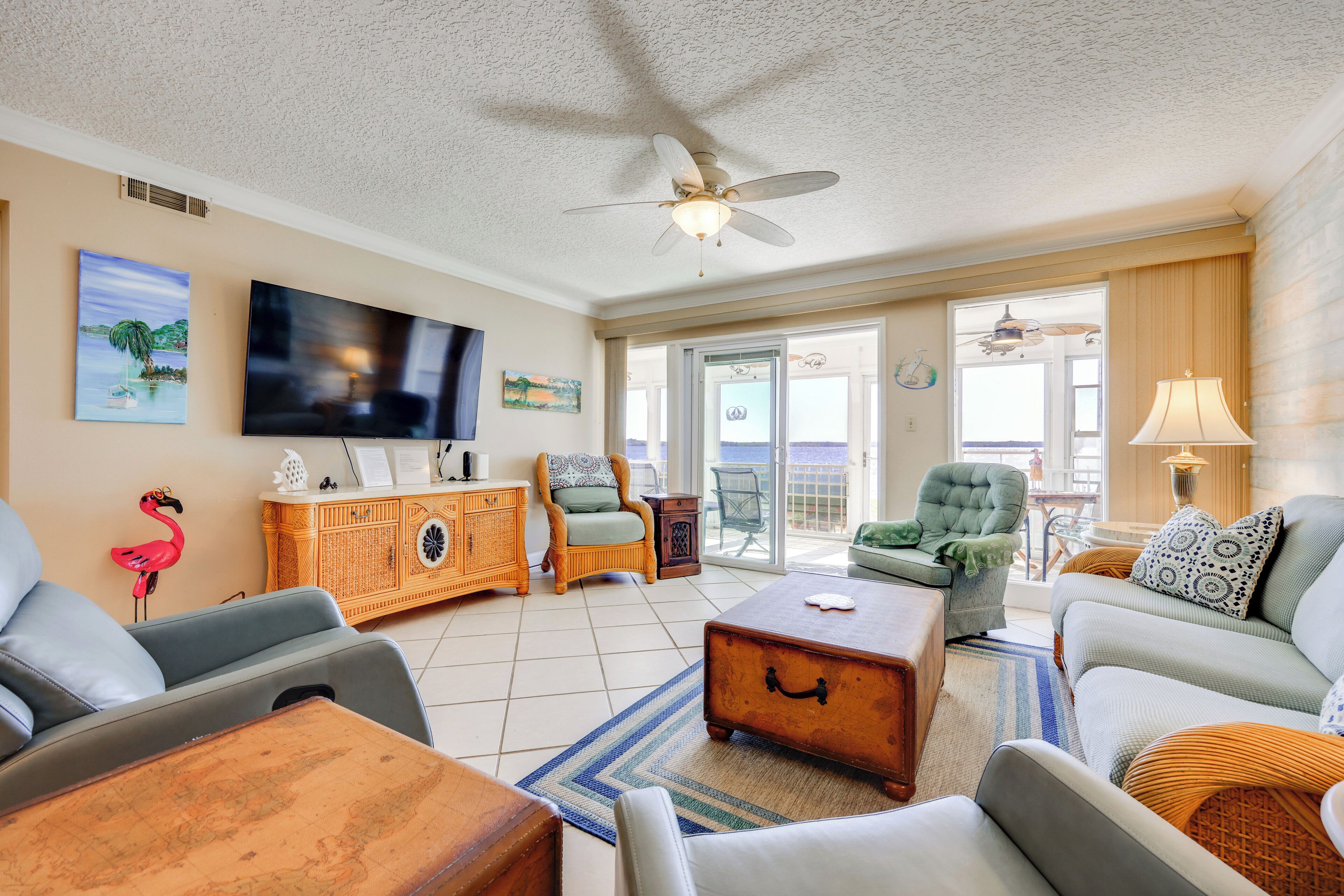 A spacious living room with a ceiling fan, a television, and a view to the outside.
