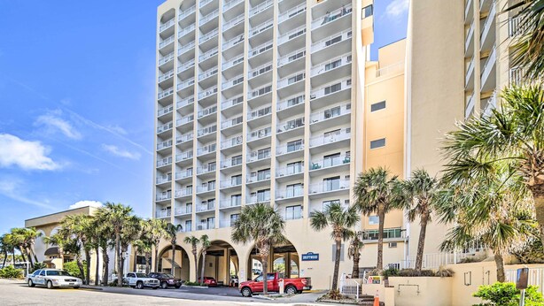 A multi-story hotel with balconies, palm trees, and a clear blue sky. - Ocean-View Balcony! Couples Escape in Myrtle Beach (Myrtle Beach)