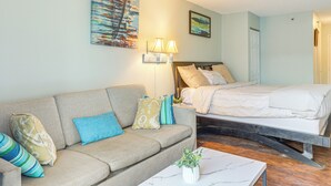 A room with a sofa, a bed, a nightstand, and a wall-mounted lamp. - Ocean-View Balcony! Couples Escape in Myrtle Beach (Myrtle Beach)