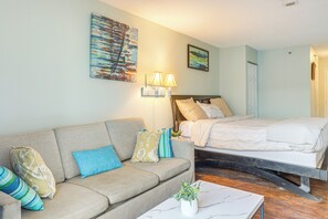 A room with a sofa, a bed, a nightstand, and a wall-mounted lamp. - Ocean-View Balcony! Couples Escape in Myrtle Beach (Myrtle Beach)