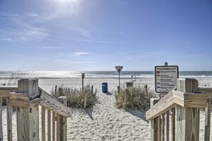 A wooden boardwalk leading to a beach with a warning sign about beach hazards. - Ocean-View Balcony! Couples Escape in Myrtle Beach (Myrtle Beach)