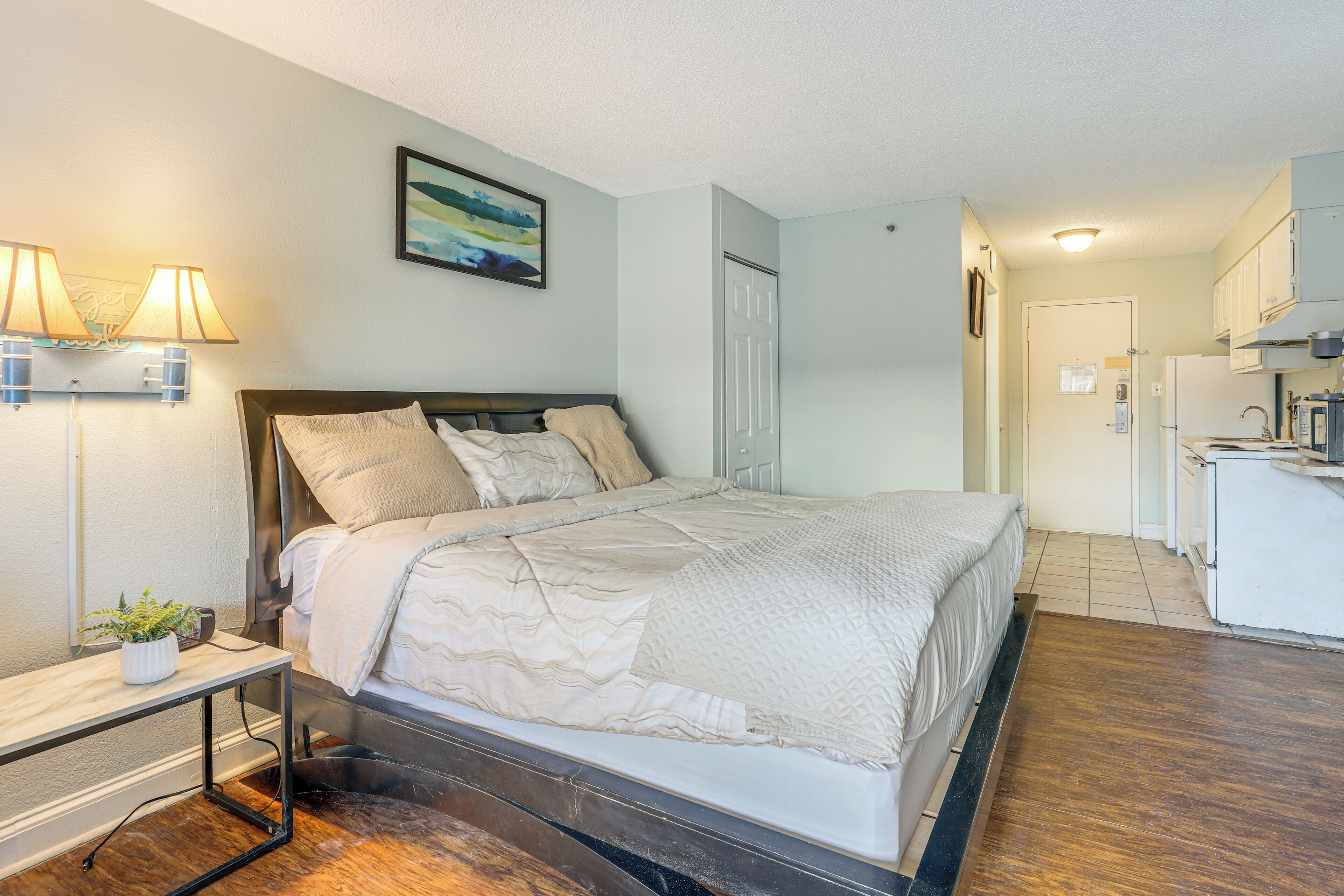 A neatly arranged bedroom with a bed, bedside table, lamp, and a small potted plant.