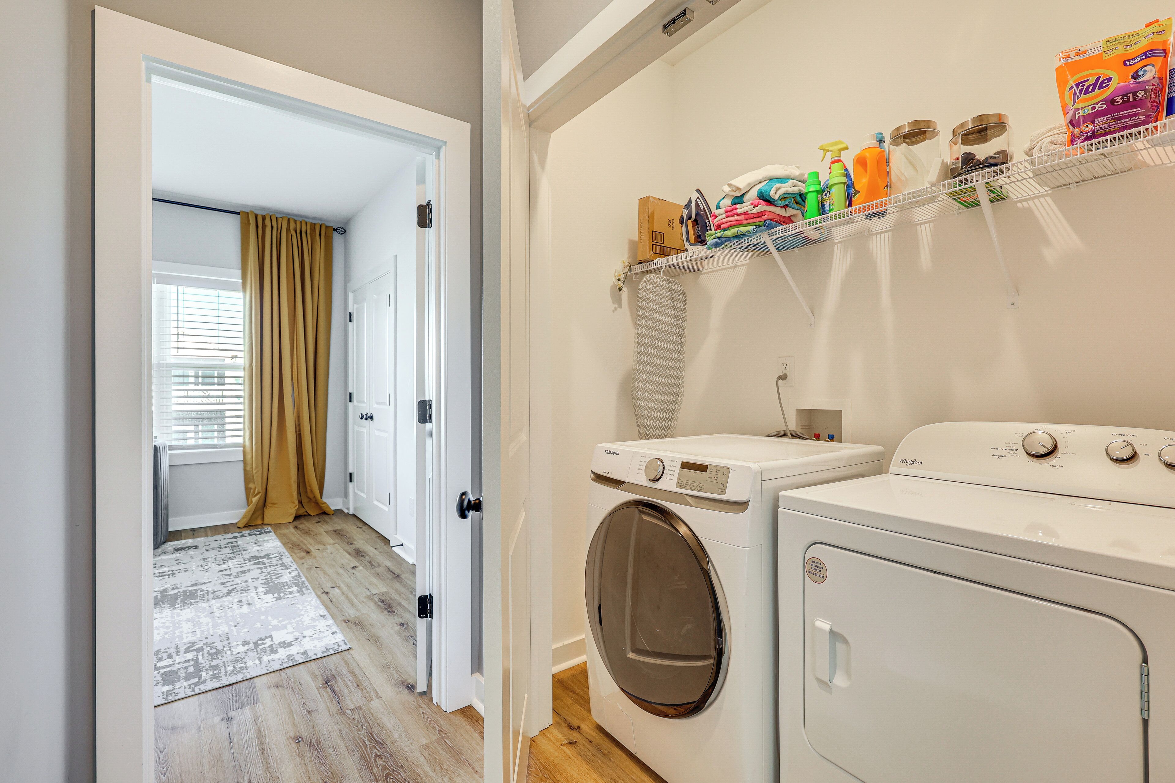 Une buanderie équipée d’un lave-linge, d’un sèche-linge et d’étagères où sont rangés les produits de nettoyage.