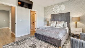 Et soveværelse med seng, loftventilator, fjernsyn, et dekorativt vægmaleri og et natbord med lamper.