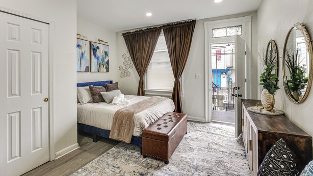A bedroom with a bed, a bench, a dresser, and a door. - Walk to Patterson Park! Pet-Friendly Townhome (Baltimore)
