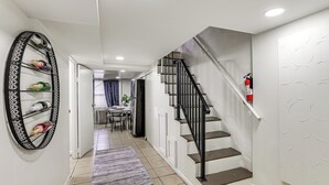 A modern interior with a staircase, a decorative wine rack, and a dining area in the background. - Walk to Patterson Park! Pet-Friendly Townhome (Baltimore)