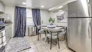 A modern kitchen with a stainless steel refrigerator, white cabinets, a dining table with chairs, and a patterned rug. - Walk to Patterson Park! Pet-Friendly Townhome (Baltimore)