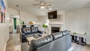 A modern living room with a fireplace, leather sofas, a flat-screen TV, and a ceiling fan. - 2 Mi to FSU: Pet-Friendly Retreat w/ Private Yard (Tallahassee)