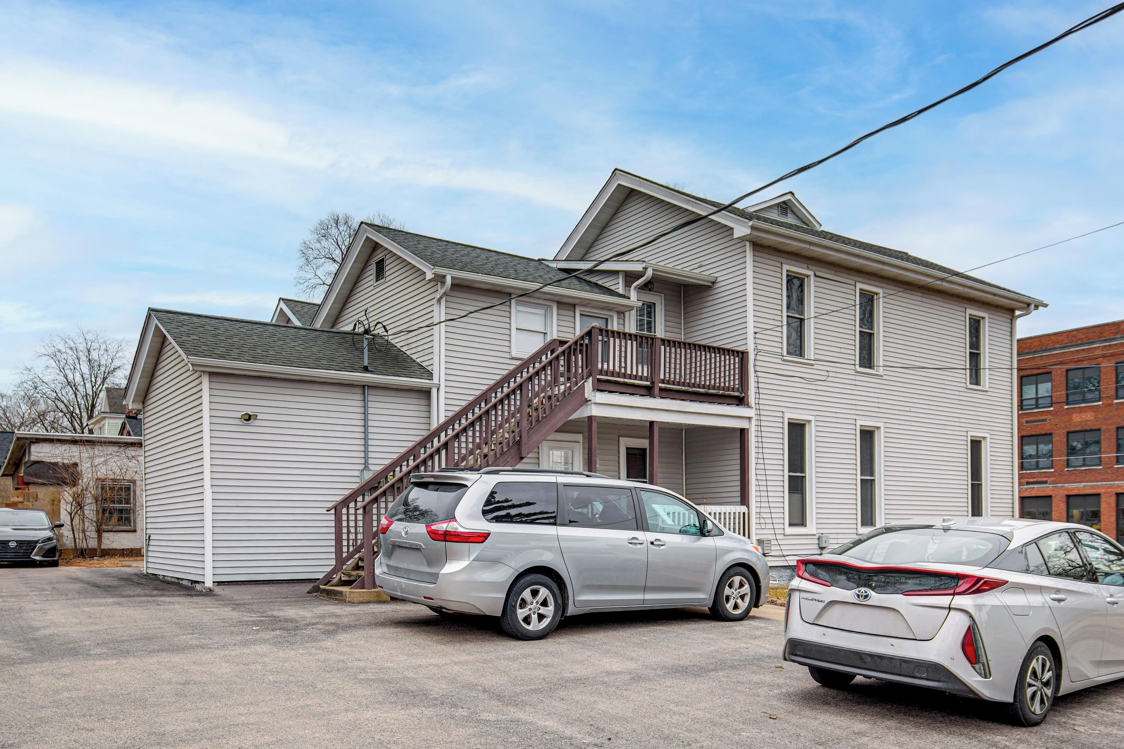 A two-story house with a garage, a staircase leading to the second floor, and two parked cars.